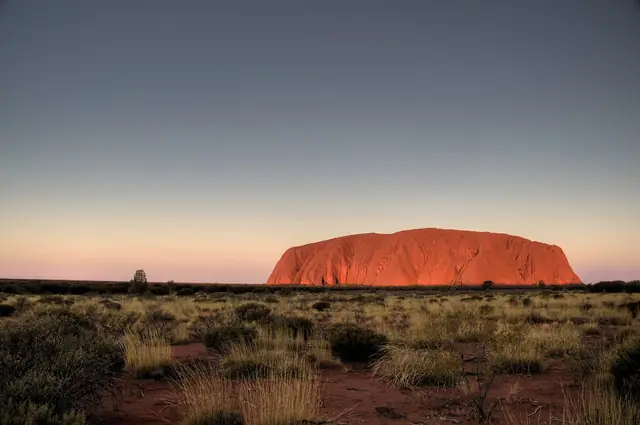 Uluru seen across the desert plain at dusk