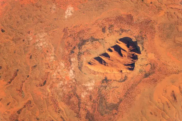 Satellite image of Uluru showing its shape and the surrounding dunes