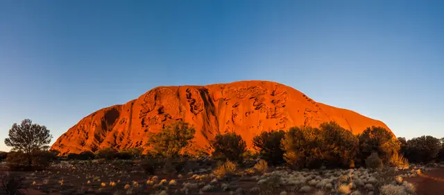 Uluru silhouetted under a pink and orange sunrise sky