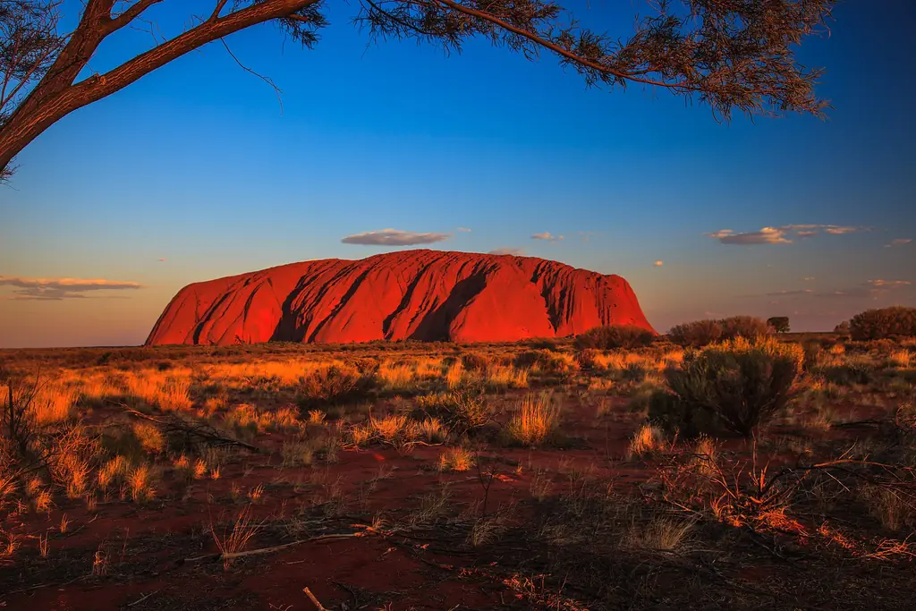 The red monolith of Uluru lit by late afternoon sun