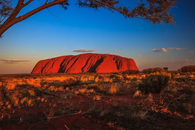 The red monolith of Uluru lit by late afternoon sun